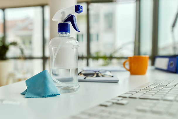 Cleaning spray bottle and a cloth on a desk in the office.  - Foto, afbeelding