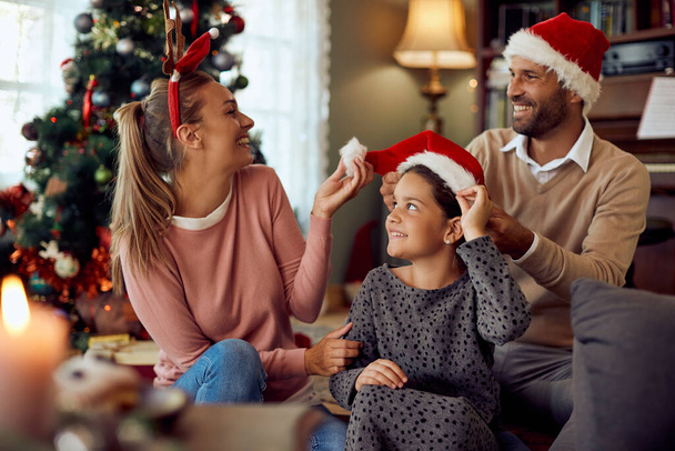 Cheerful parents and their daughter having fun on Christmas day at home. - Photo, Image