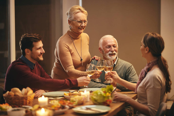 Щаслива сім'я святкування і тости з вином під час їжі за обіднім столом
.  - Фото, зображення