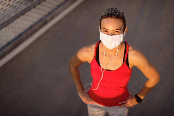 High angle view of sportswoman with protective face mask standing outdoors and looking at camera.  - Foto, afbeelding