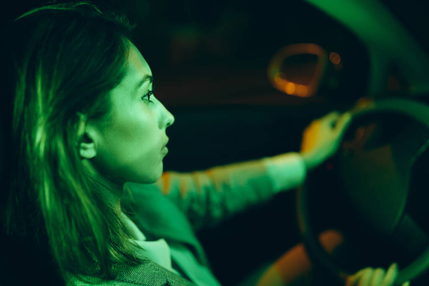 Close-up of pensive woman driving car alone at night. - Foto, Imagen