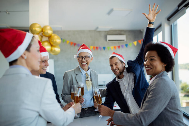 Glückliche reife Geschäftsfrau und ihre Kollegen stoßen mit Champagner an, während sie auf der Weihnachtsfeier im Büro feiern. - Foto, Bild
