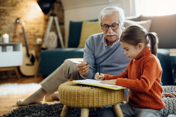 Small girl and her grandfather enjoying in creative tie and coloring together at home.  - Фото, изображение