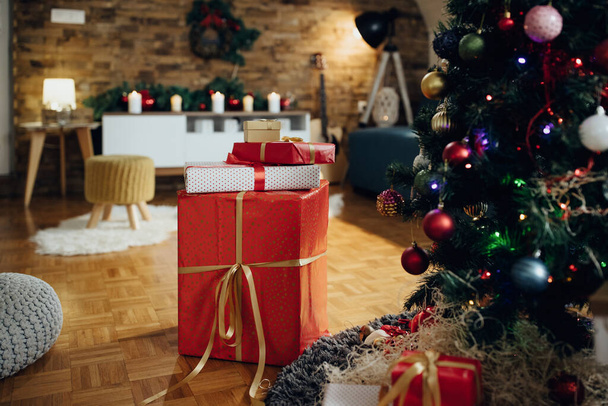 Загорнуті подарунки під деревом у вітальні на Різдво вранці
.  - Фото, зображення