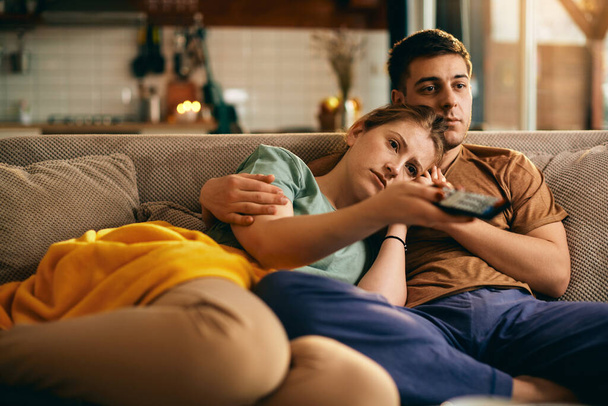 Young woman using remote control and changing channels watching TV with her boyfriend at home.  - Fotoğraf, Görsel