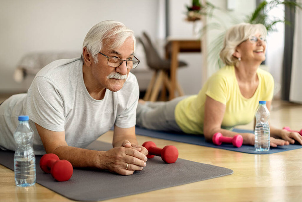 Mature man and his wife working out on the floor at home.  - Valokuva, kuva