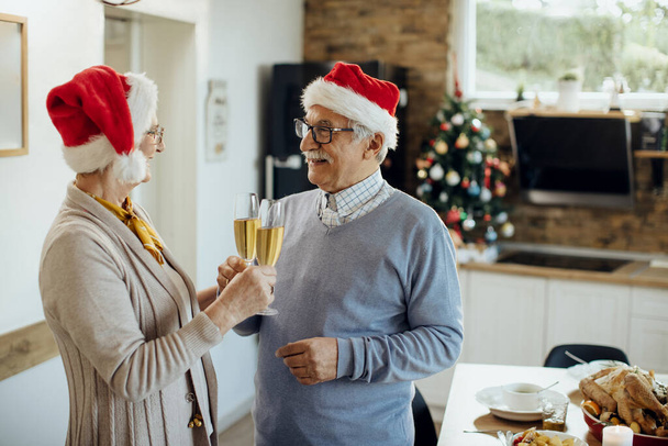 Happy mature husband and wife celebrating Christmas and toasting with Champagne at home.  - Foto, Bild