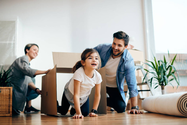 Грайлива сім'я розважається з картонними коробками, переїжджаючи в новий будинок. Фокус на дочці
.  - Фото, зображення