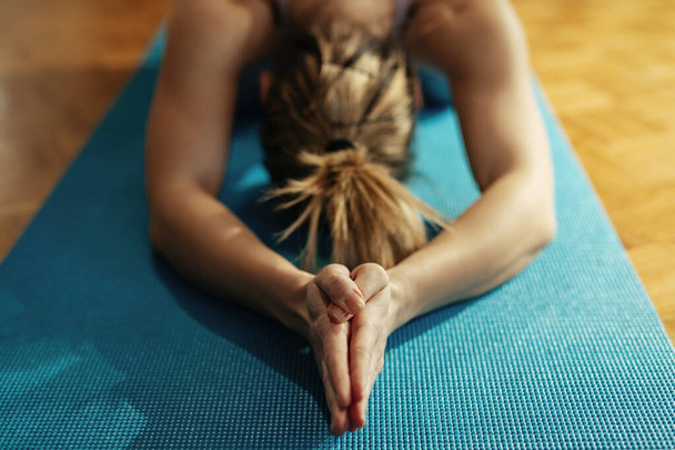 Close-up of woman with hands cupped doing stretching exercises on the floor.  - Valokuva, kuva