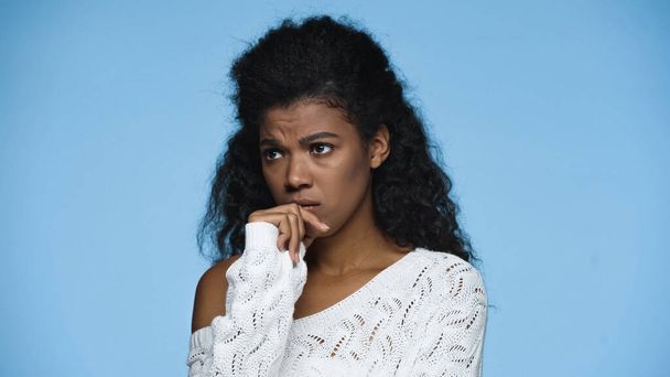 worried african american woman in white knitted sweater frowning isolated on blue - Фото, зображення