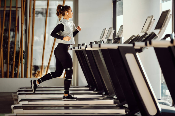 Full length of female athlete running on treadmill in a gym. Copy space. - Foto, Bild