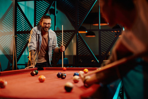Smiling man playing snooker with is girlfriend in a pool hall. - Foto, imagen