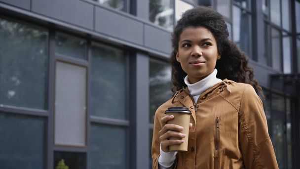 mladá africká americká žena držící kávu jít na městské ulici - Fotografie, Obrázek
