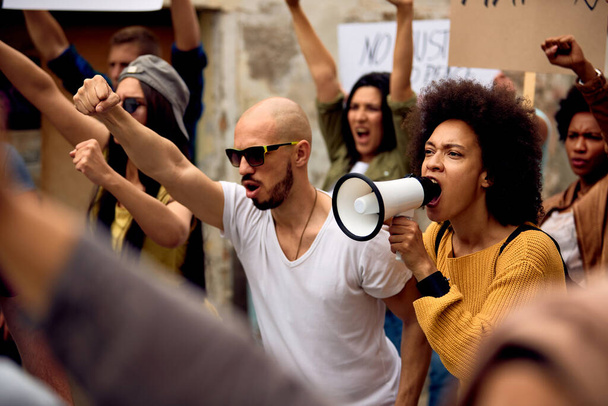 Young black woman shouting through megaphone on anti-racism solidarity protest.  - Foto, imagen
