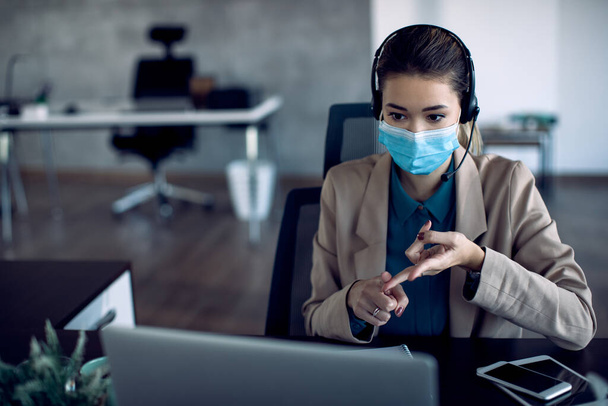 Businesswoman talking during conference call over laptop in the office due to COVID-19 pandemic. - Φωτογραφία, εικόνα