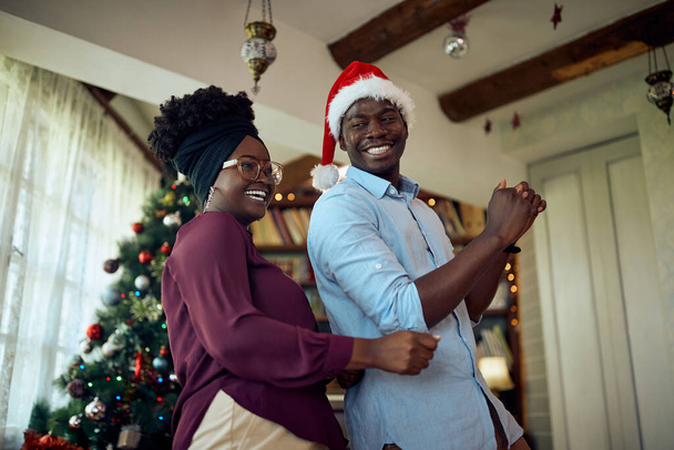 Low angle view of African American carefree having fun and dancing while celebrating Christmas at home. - Fotó, kép