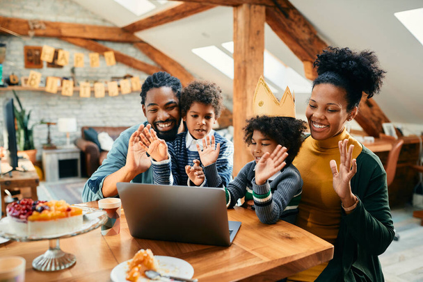 Happy African American family celebrating daughter's Birthday and waving to someone during video call over laptop at home. - Fotografie, Obrázek