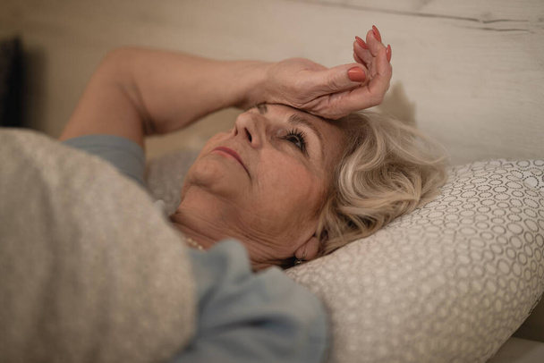 Pensive zralá žena pocit nespavosti při ležení v posteli pozdě v noci.   - Fotografie, Obrázek
