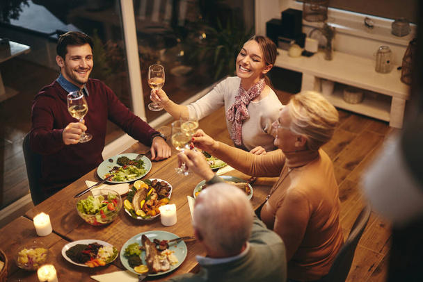 Високий кут зору щасливої сім'ї святкування і тости з вином, маючи при цьому їжу за обіднім столом
.  - Фото, зображення