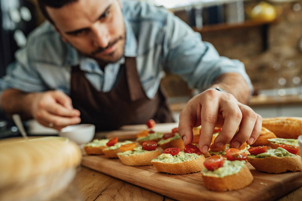 Close-up of chef adding cherry tomato on top of bruschetta while preparing food in the kitchen.  - Fotoğraf, Görsel