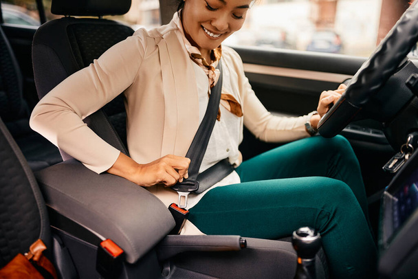 Happy Asian businesswoman fastening seatbelt while driving car. - Foto, immagini