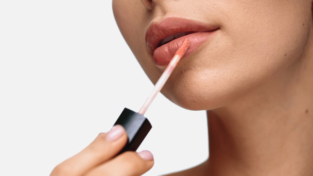cropped view of young woman applying lip gloss isolated on white  - Fotografie, Obrázek