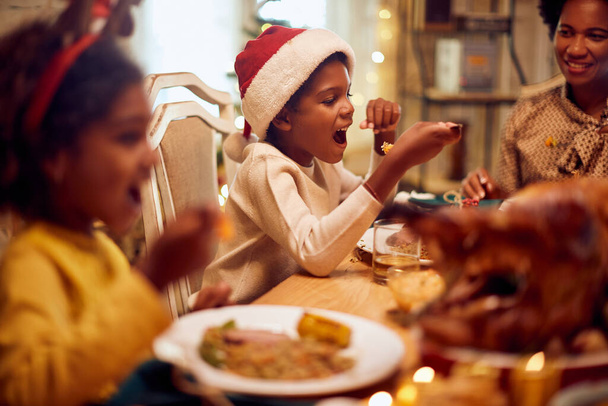 African American little boy eating with his family at dining table on Christmas day.  - Valokuva, kuva