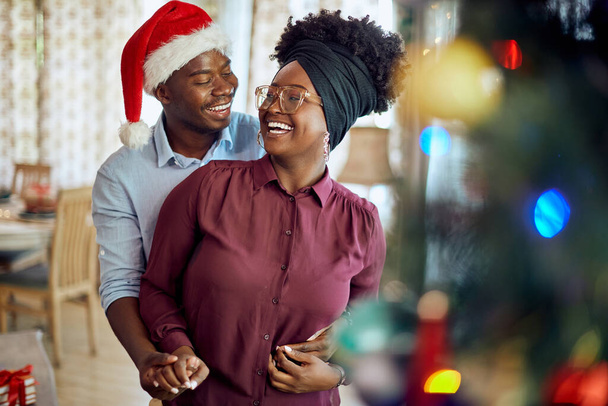 Happy black woman and her husband having fun while celebrating Christmas together a home. - Foto, afbeelding
