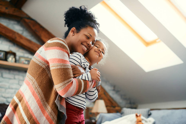 Afro-Amerikan anne ve kızını sevmenin düşük açılı görüntüsü evde gözleri kapalı kucaklaşmak.  - Fotoğraf, Görsel