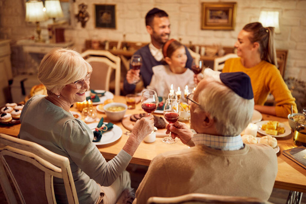 Happy senior Jewish couple toasting with wine during family dinner on Hanukkah.  - Photo, image