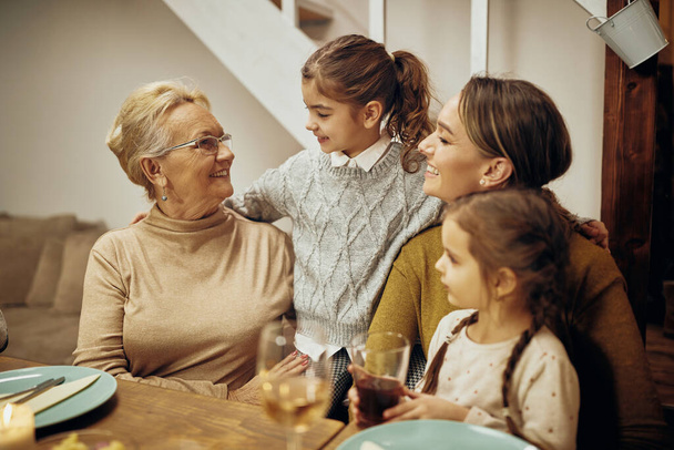 Happy senior woman communicating with her granddaughters and daughter at dining table. - Φωτογραφία, εικόνα