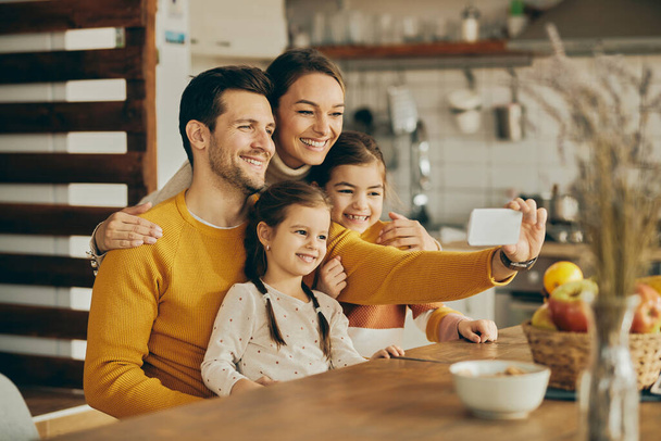 Happy parents with two daughters taking selfie with smart phone at home.  - Foto, Bild