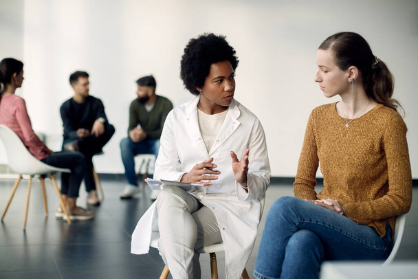 Africký americký psychoterapeut a mladá žena komunikuje při setkání skupiny.  - Fotografie, Obrázek