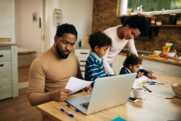 African American man working at home while mother is helping their children with a homework.  - Foto, immagini
