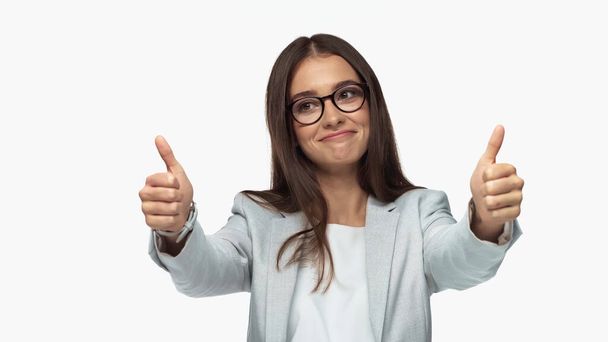 successful businesswoman in eyeglasses smiling and showing thumbs up isolated on white - Foto, Imagem