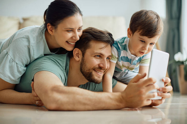 Happy parents with son using touchpad and taking selfie at home.  - Φωτογραφία, εικόνα