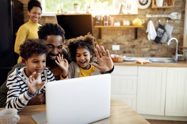Happy African American father and his children waving while using computer and making video call at home.  - Foto, Bild