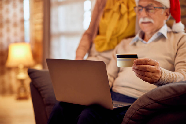 Close-up of senior man and his wife home shopping with laptop and credit card during Christmas holidays. - Photo, image