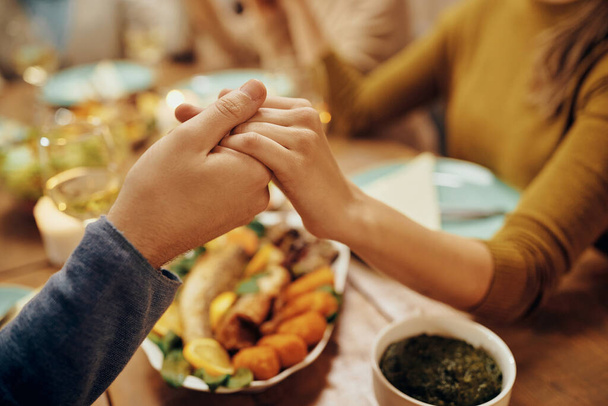 Close-up of couple holding hands while saying grace during family lunch at dining table. - Foto, immagini