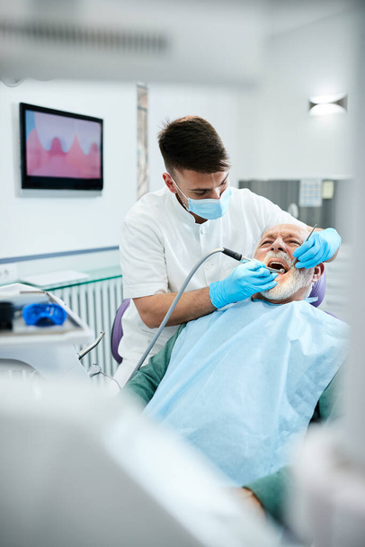 Senior man having dental drill procedure during medical appointment with dentist at dental clinic.  - Fotografie, Obrázek
