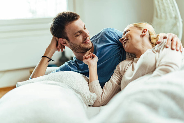 Happy couple lying down in bed and having fun while communicating in the morning.  - Φωτογραφία, εικόνα