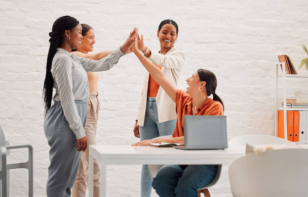 Four happy businesswomen joining their hand together in an office at work. Diverse group of cheerful businesspeople giving each other a high five for support. - Foto, imagen