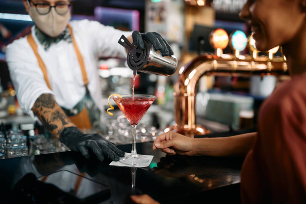 Крупним планом бармен, який обслуговує коктейль для жінок-клієнтів під час роботи в барі під час пандемії коронавірусу
. - Фото, зображення