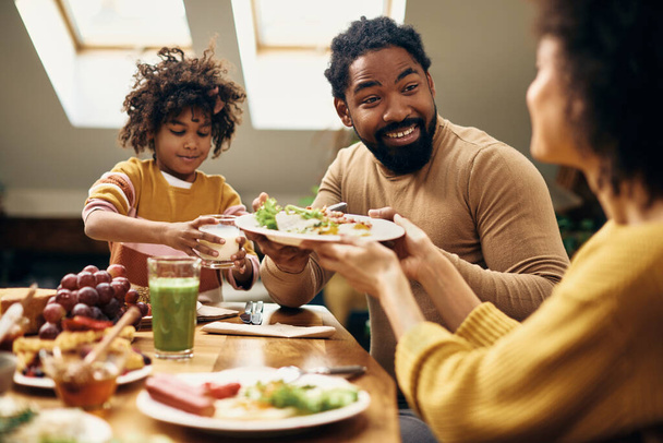 African American family having a meal together at dining table. Focus is on happy man. - Foto, Imagem