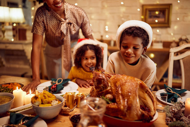 Happy African American family having traditional roasted turkey for Christmas lunch at home. Focus is on boy. - Valokuva, kuva