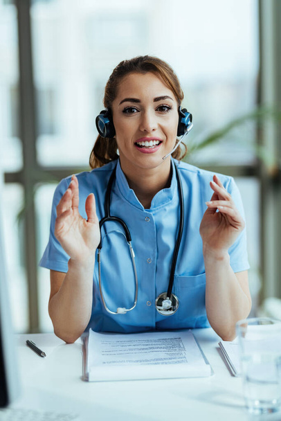 Smiling healthcare worker with headset working at hospital call center and looking at camera.  - Photo, image