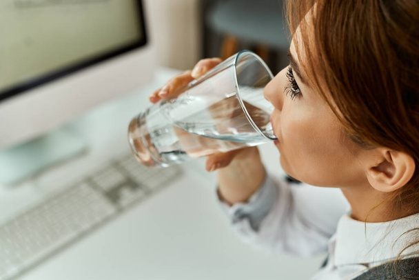 Close-up of businesswoman having a glass of water while working un the office.  - Foto, Imagen