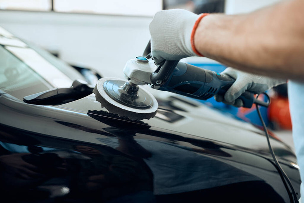 Close-up of man polishing car while working at auto service workshop - Fotó, kép