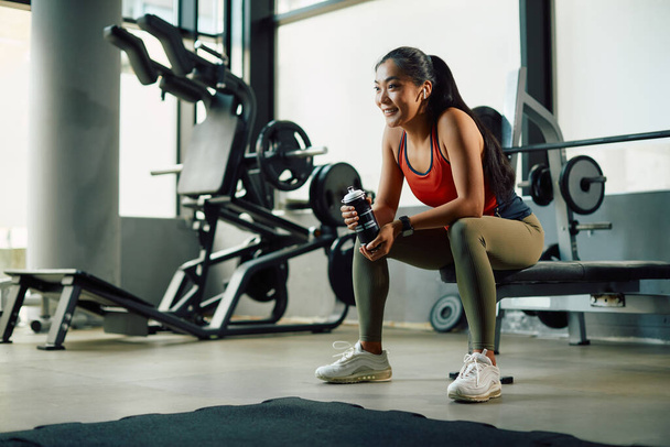 Happy Asian sportswoman having a water break while working out in a gym.  - Foto, immagini