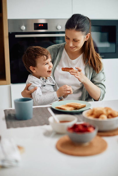 Happy little boy having breakfast with is mother at dining table at home. - Photo, Image